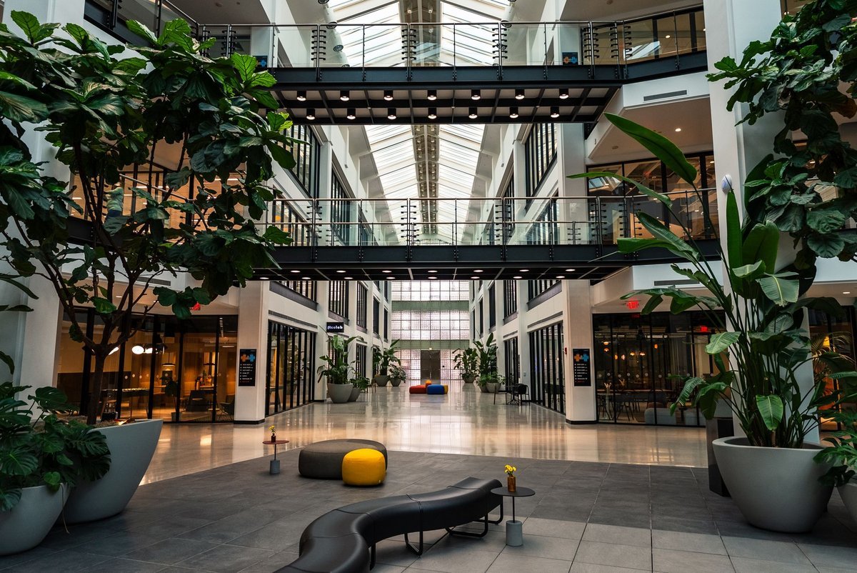 Modern office atrium with glass walkways and planted seating areas