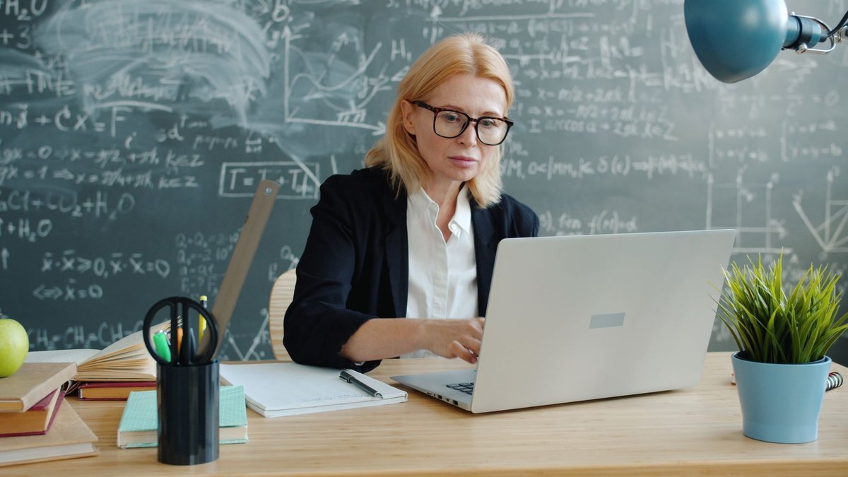 Faculty member working at a laptop in front of a chalkboard