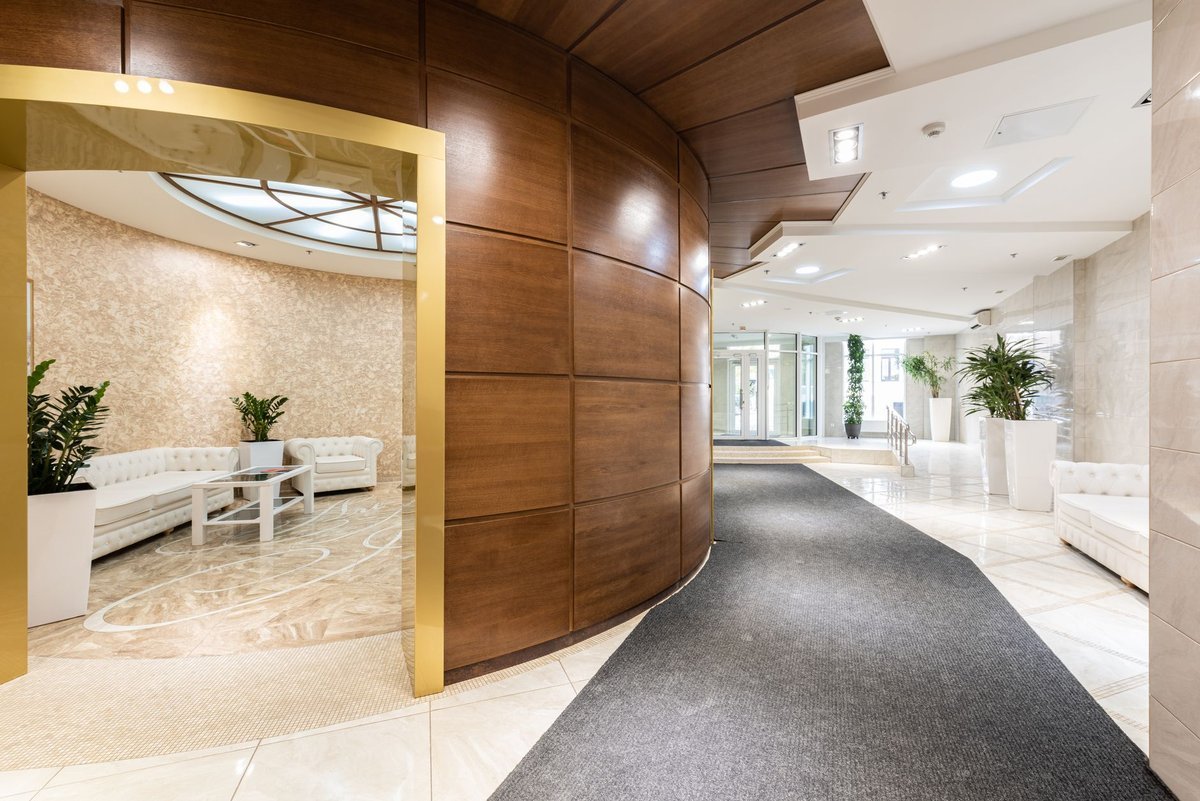 Bright marble hotel lobby with seating areas and daylight from the entrance
