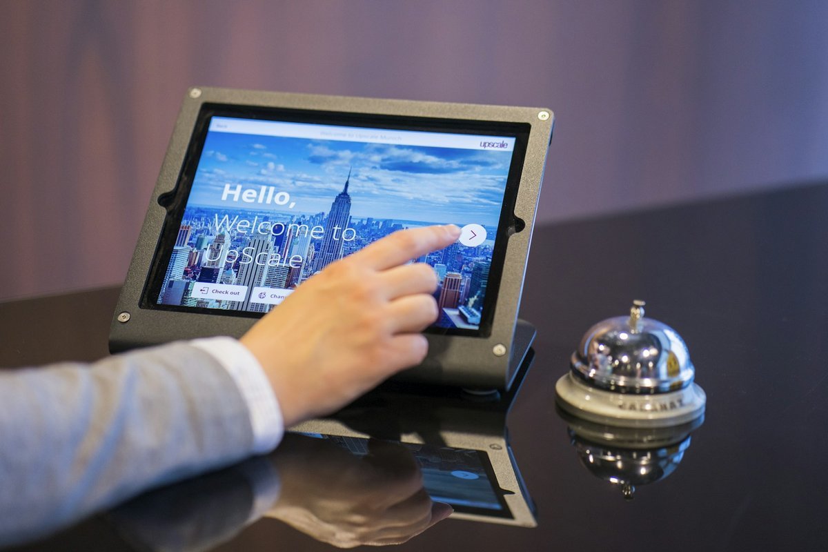 Guest using a self check-in tablet beside a reception bell