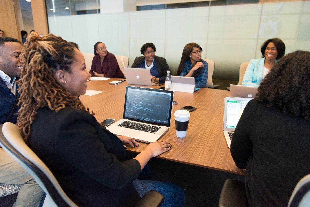 Professional services team meeting around a boardroom table with laptops