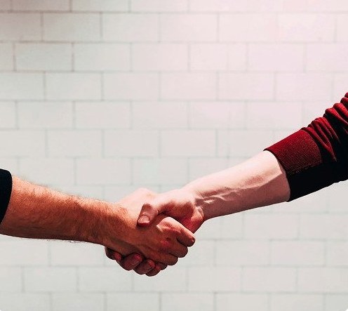 A firm handshake against a light brick wall