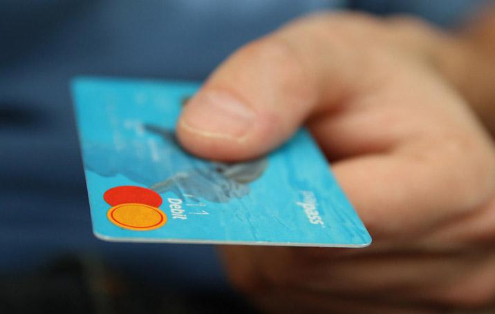 Hand offering blue debit card.