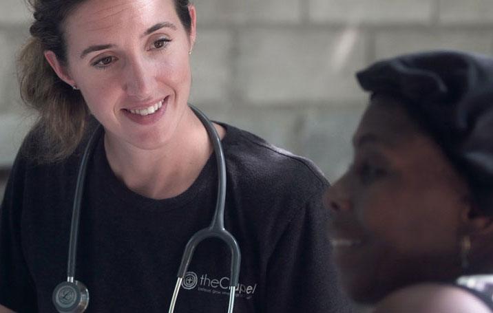 Medical professional with stethoscope smiling at patient.