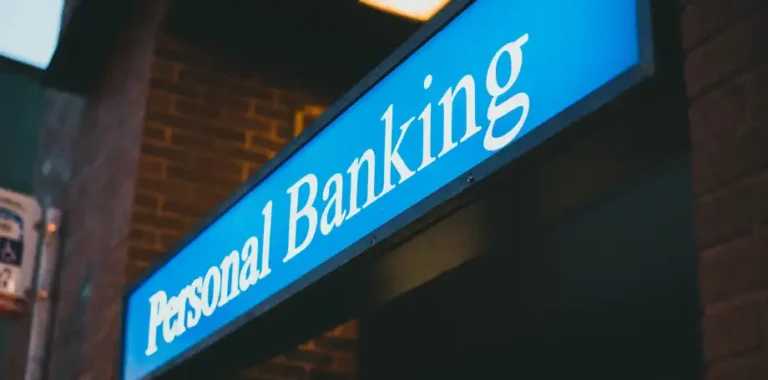 Blue illuminated Personal Banking sign on brick.