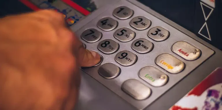 Finger pressing button on ATM keypad.