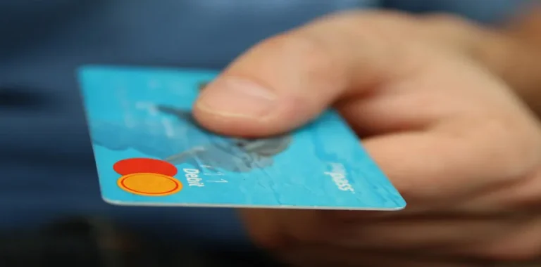 Hand offering a blue Mastercard debit card.