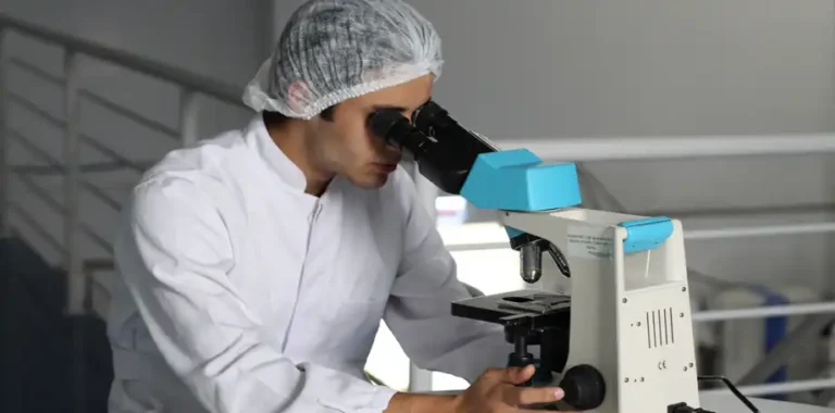 Man in lab coat using a microscope.