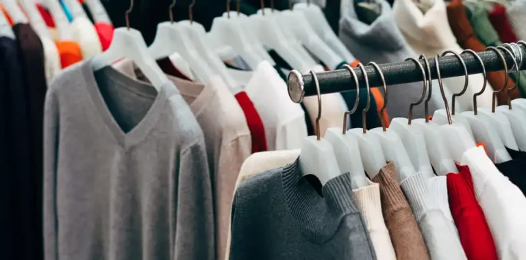 Clothing rack with various sweaters and shirts on hangers.