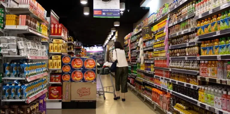 Woman pushing shopping cart in a grocery store aisle.