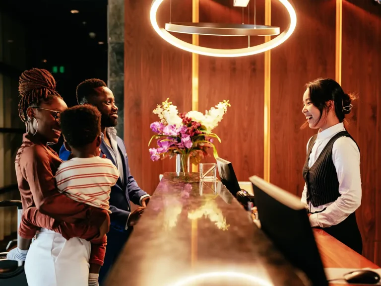 Family checking in at hotel reception, smiling with attendant.