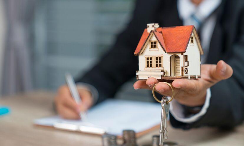 Real estate agent holding house model and keys, signing contract.