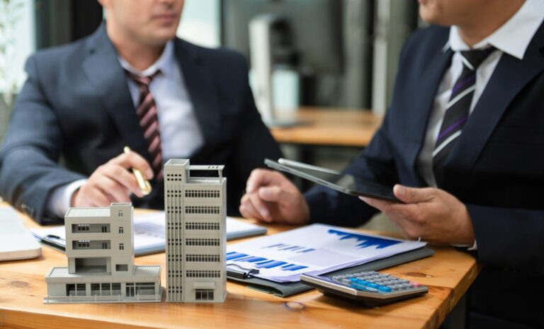 Real estate developers reviewing building models and financial charts.