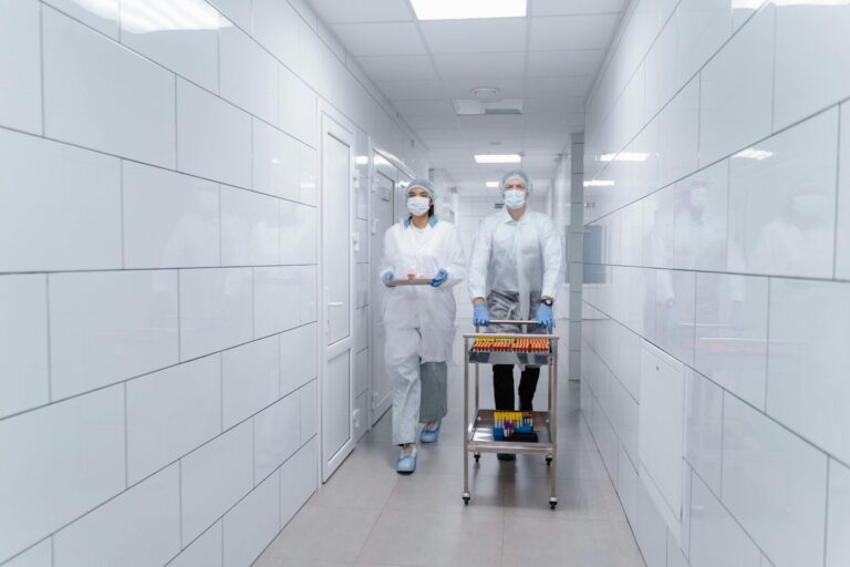 Lab technicians transport medical samples through a clean, tiled corridor.