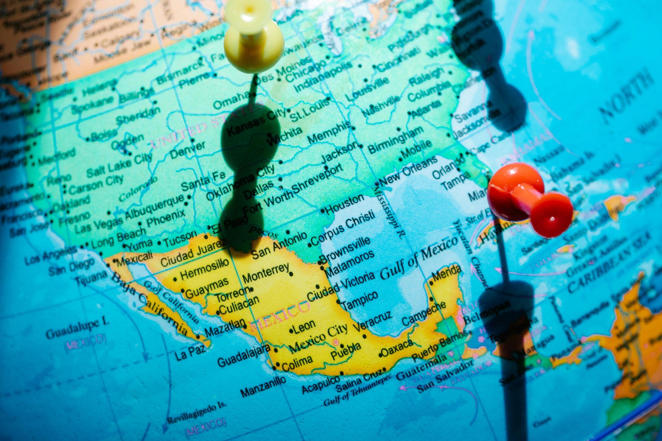 Pushpins marking cities on a globe of North America.