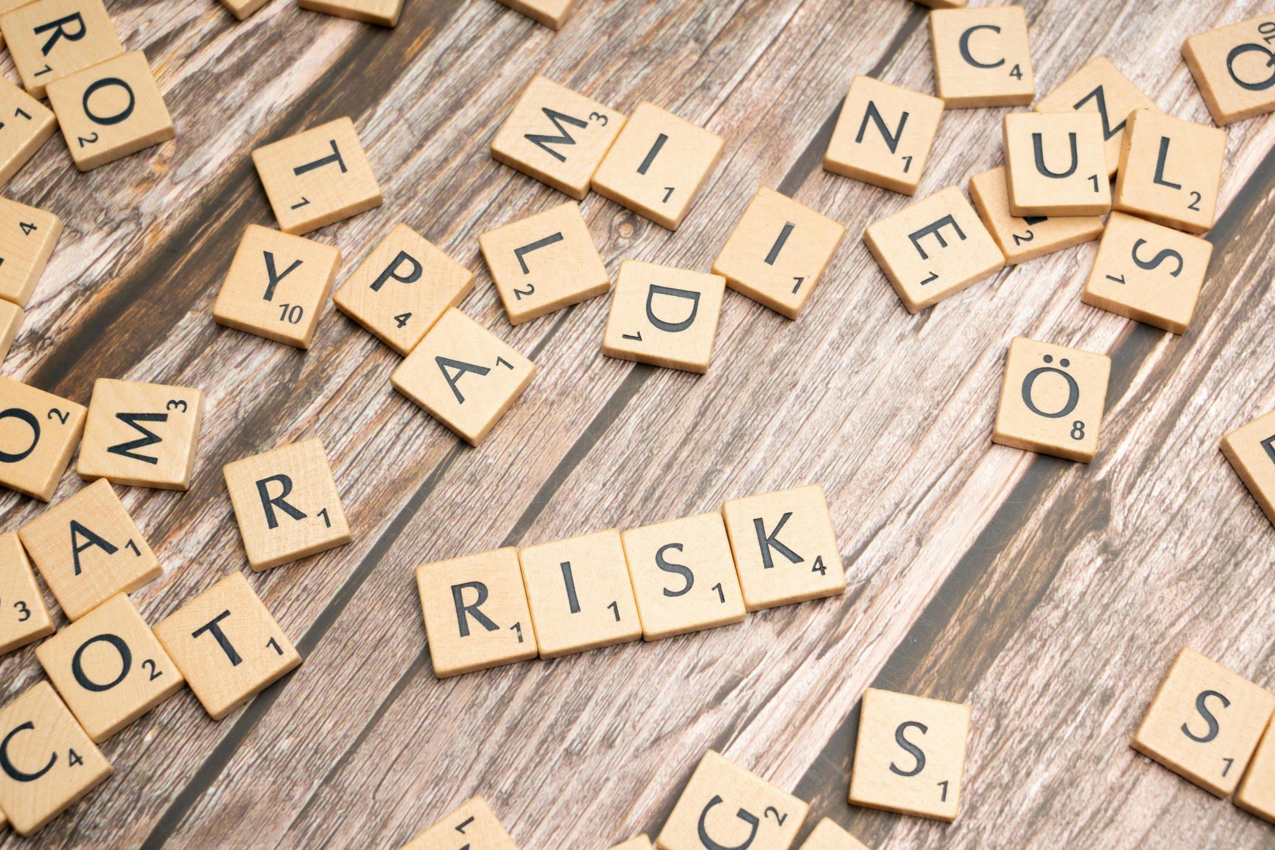 Scrabble tiles spelling RISK on a wooden table.