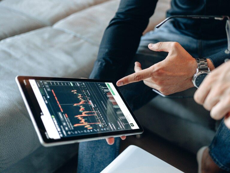 Two people analyzing financial charts on a tablet.