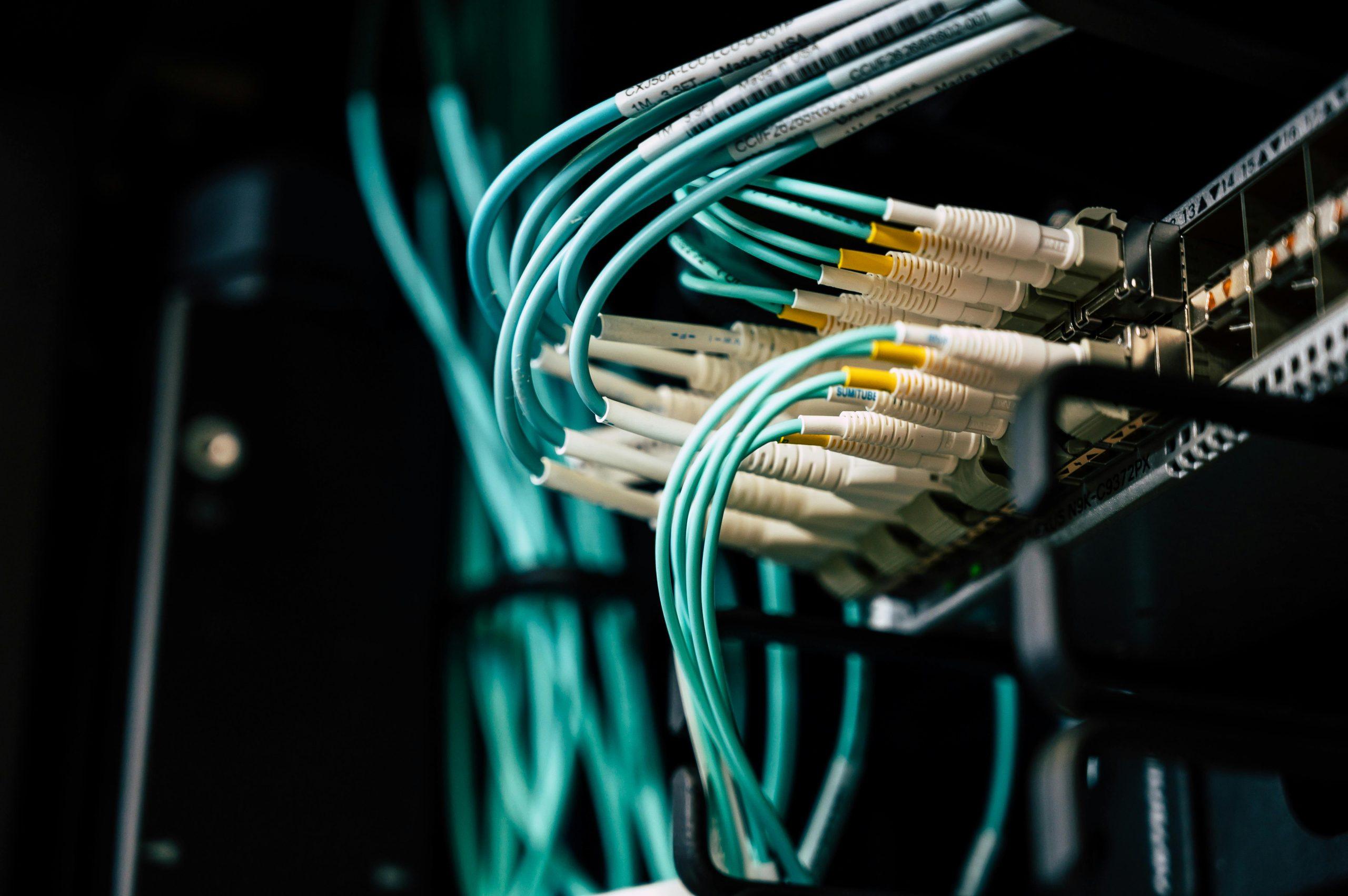 Teal fiber optic cables plugged into a network switch.