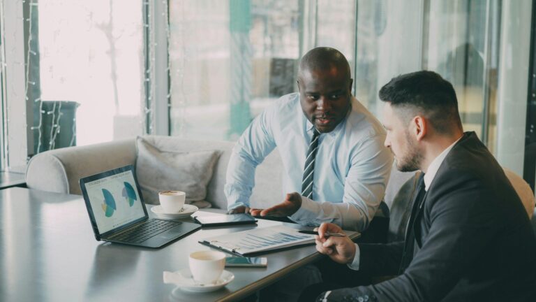 Two business colleagues discussing data with laptop and papers.