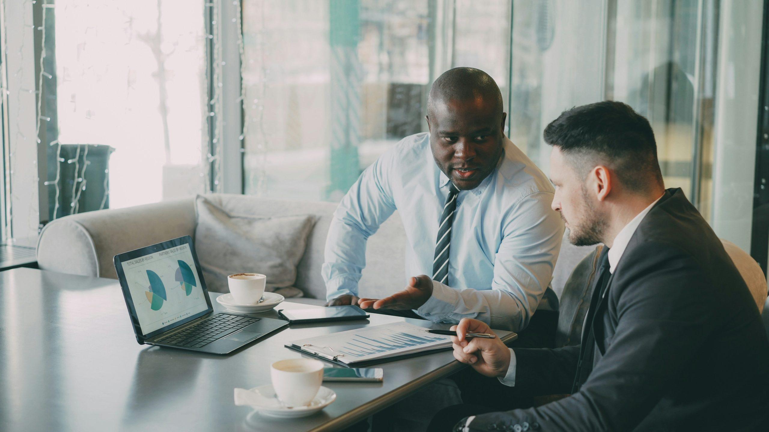 Two business colleagues discussing data with laptop and papers.