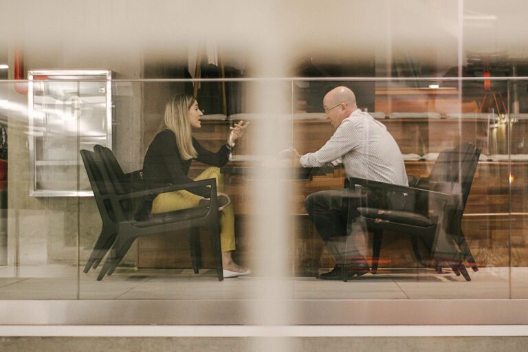Woman and man conversing, viewed through glass.