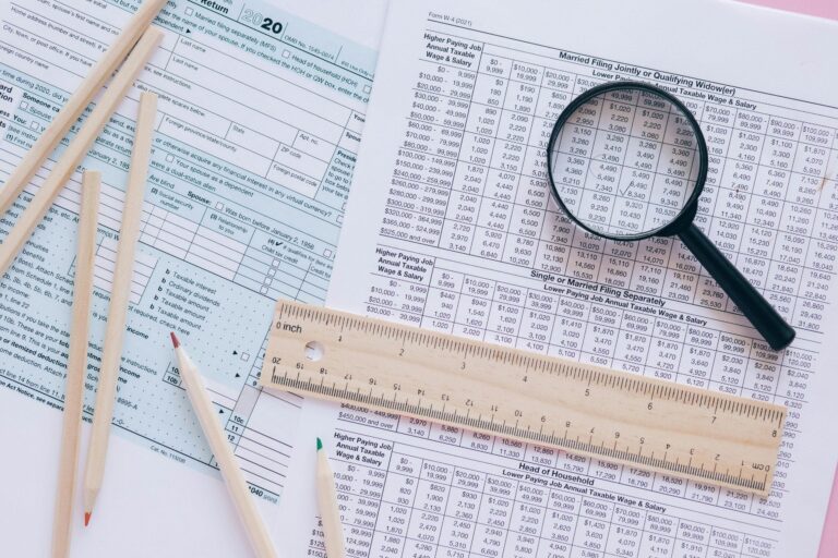 Tax forms, pencils, ruler, and magnifying glass for tax preparation.
