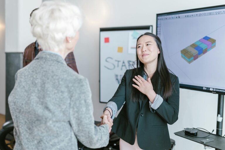 Two women shaking hands in a modern office.