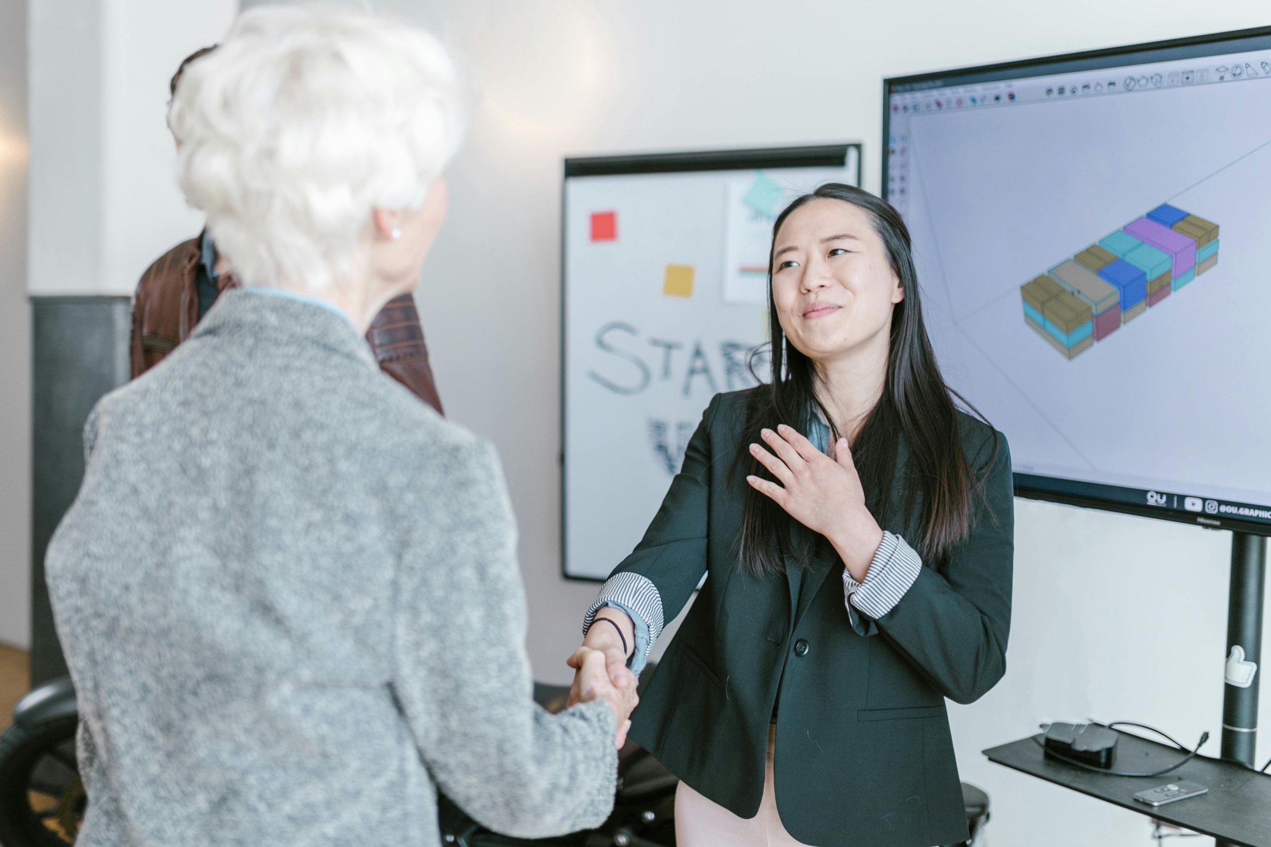 Two women shaking hands in a modern office.