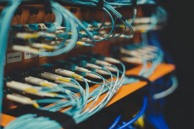 Blue fiber optic cables plugged into an orange patch panel.