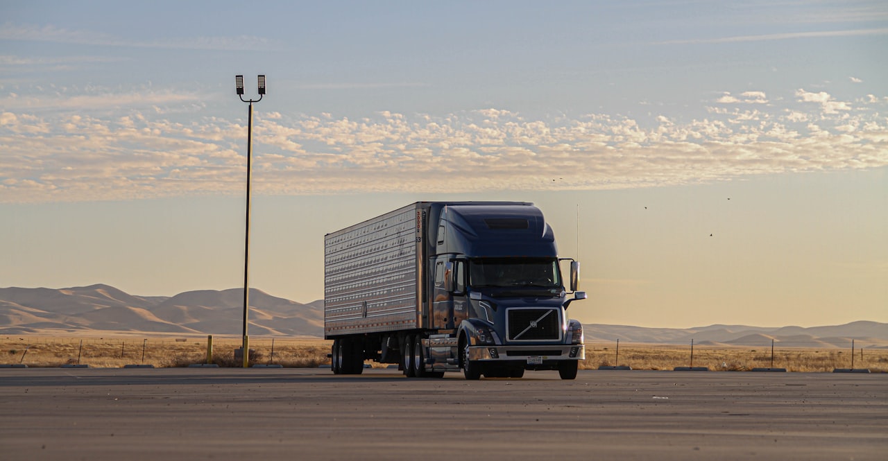 Semi truck and trailer parked alone at a highway rest area at sunset