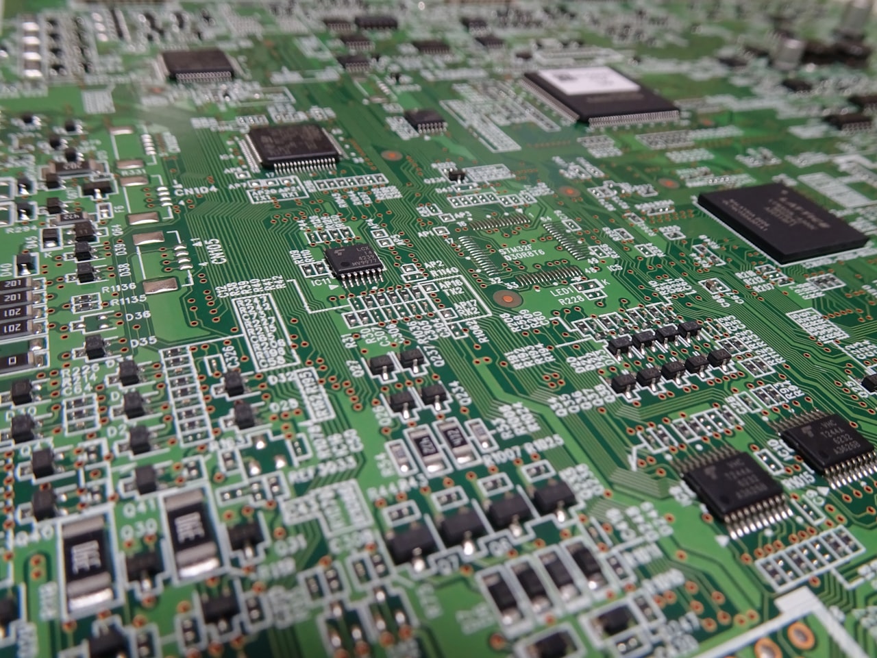 Close-up of a populated green printed circuit board showing surface-mount components