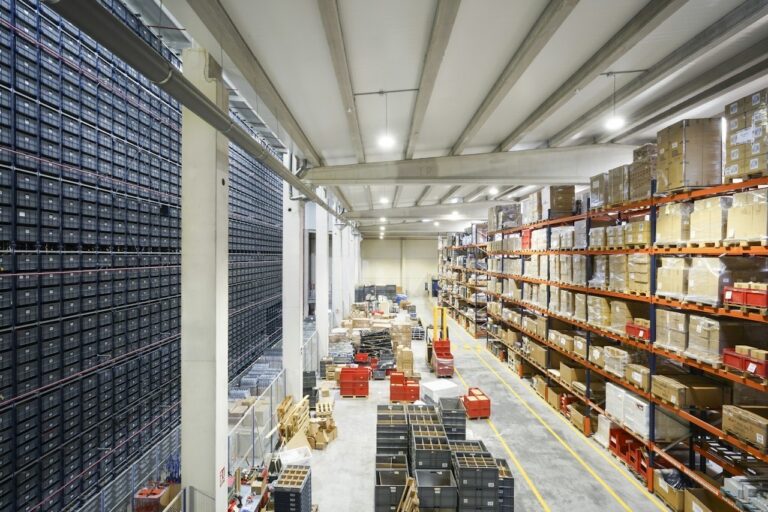 Large warehouse with long rows of organized shelving and labeled storage bins