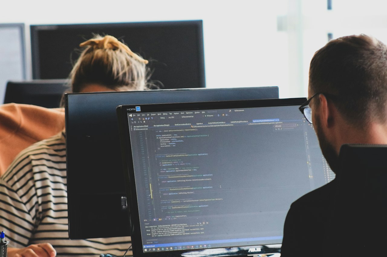 Software engineers working at code on desktop monitors in a shared office
